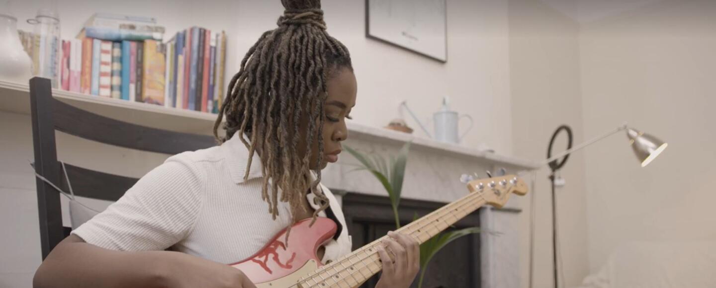 MEI sat down indoors playing the guitar