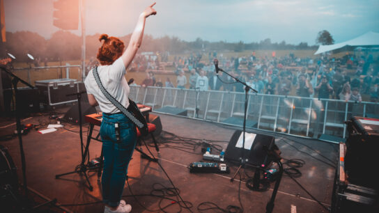 A guitarist performs in front of an outdoor audience